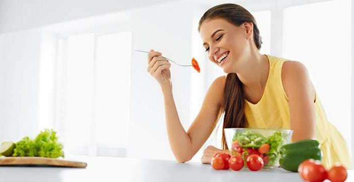 smiling woman with fruits and vegetables in the kitchen