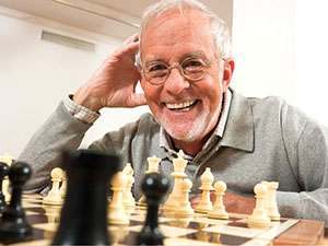 portrait of haapy elderly man playing chess