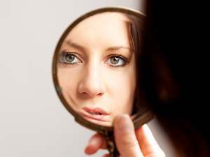 photo of a woman looking her self at the mirror