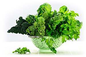 Dark green leafy vegetables in colander that are very helpful for healthy hair purposes