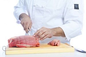 chef sliced raw meat using knife and chopping board