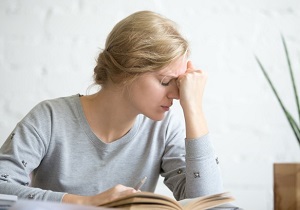 Portrait of a young overworked student girl sitting at the table